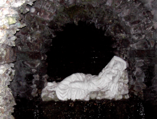 Photo of a reclining statue in a grey grotto, depicting the Goddess Persephone, for spring equinox activities