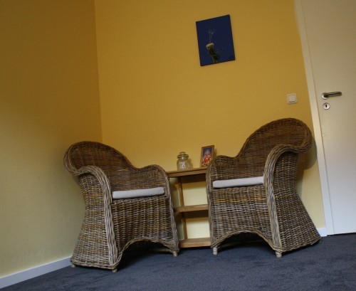 Photo von einer Zimmerecke, in der zwei Korbsessel stehen, dazwischen ein Tischchen.