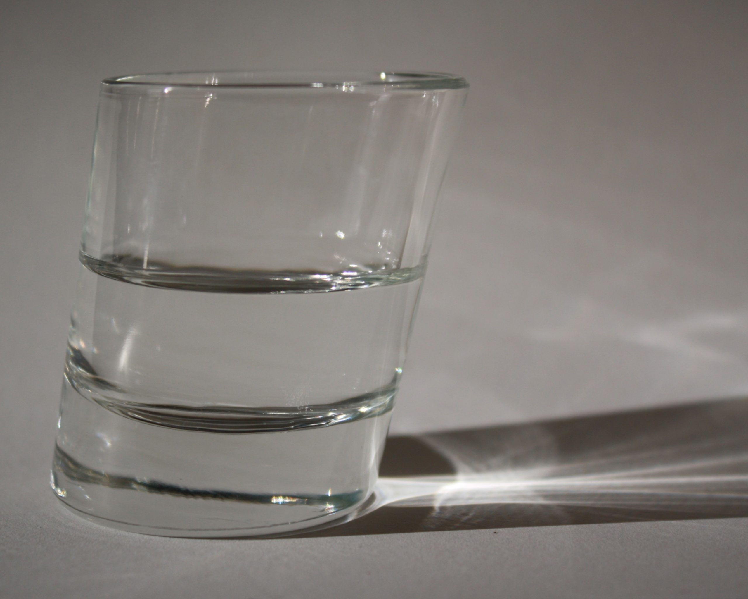 perspektiven: ein Photo von einem schrägen Glas, das zur Hälfte mit Wasser gefüllt ist.