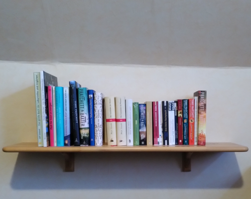 Eine Reihe Bücher auf einem Bord and der Wand