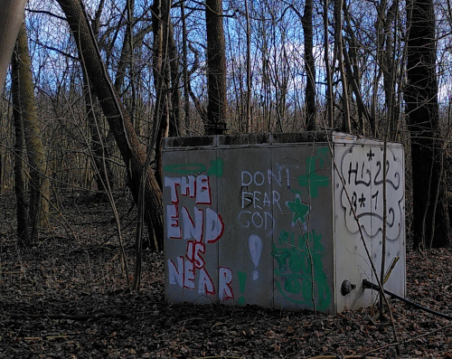 Rückblick 23 Ein Stromkasten im Wald, darauf das Graffiti: The end is near. Don't fear God!