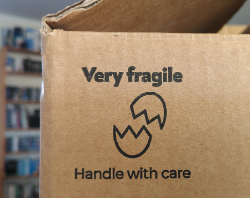 Photo von der Ecke eines Pappkartons, auf dem steht: Very fragile, handle with care.