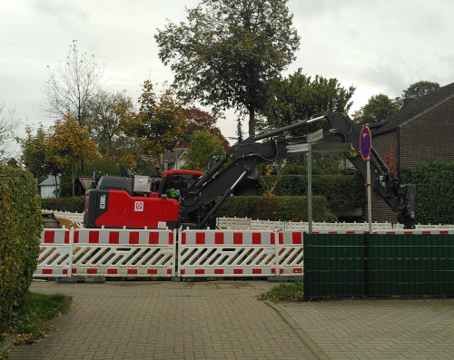 Monatsrückblick Oktober 24: Photo aus einer Straßeneinfahrt heraus, die mit Baustellenabsperrungen blockiert ist. Hinter der Absperrung steht ein großer Bagger.