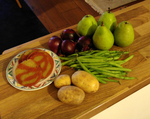 vegan Herbst: Ein Photo von vier Birnen, drei Kartoffeln, vier Zweibeln, einer Handvoll grünen frischen Bohnen und Einen Teller, darauf rosa-weiß-marmorierter Seitan.