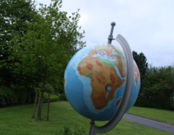 Photo von einem großen Globus draußen auf einer Wiese. Im Hintergrund Bäume und Sträucher. Für ideales Internet