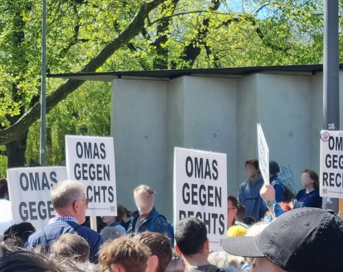 Demo, die Gesichter der Teilnehmenden sind unkenntlich verwischt. Sie halten Schilder mit der Aufschrift: Omas gegen rechts.