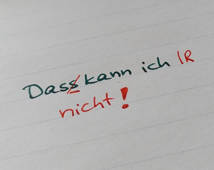 Nahhaufnahme von einem Notizzettel, auf dem steht "das kann ich nicht". Dabei hat das Das zwei s und dieser Fehler ist mit roter Tinte angestrichen. Auch das nicht ist mit roter Tinte geschrieben.