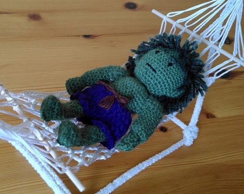 Photo in Nahaufnahme. Eine grüne gehäkelte Figur, die den Hulk darstellen soll, liegt auf dem Rücken in einer kleinen gehäkelten Hängematte. Der Hulk ist von oben abgebildet. Für Projekt52 Juni 25