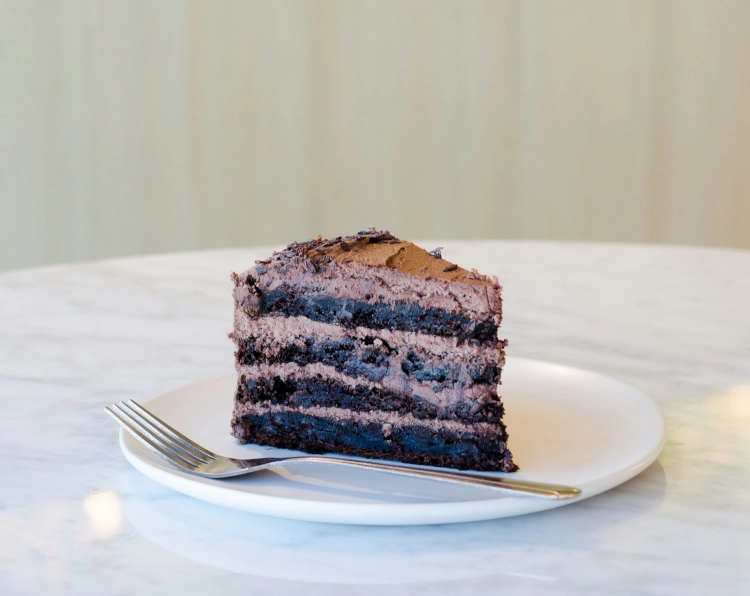 Photo of a slice of chocolate layer cake with chocolate buttercream.