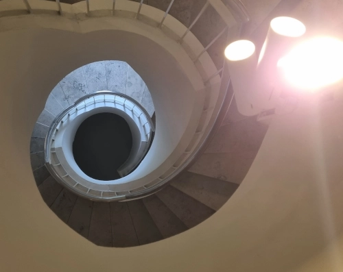 Blick von oben in ein spiralförmiges Treppenhaus.