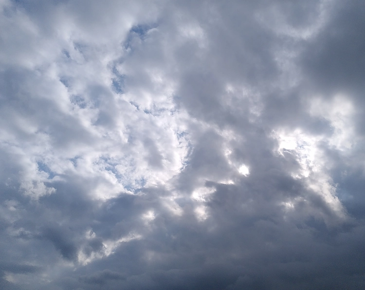 Photo von einem dramatisch bewölkten Himmel, das Licht der Sonne bricht an mehreren Stellen durch