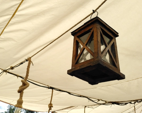 Eine Holzlaterne an einer hellbraunen Zeltdecke hängend, von unten fotografiert