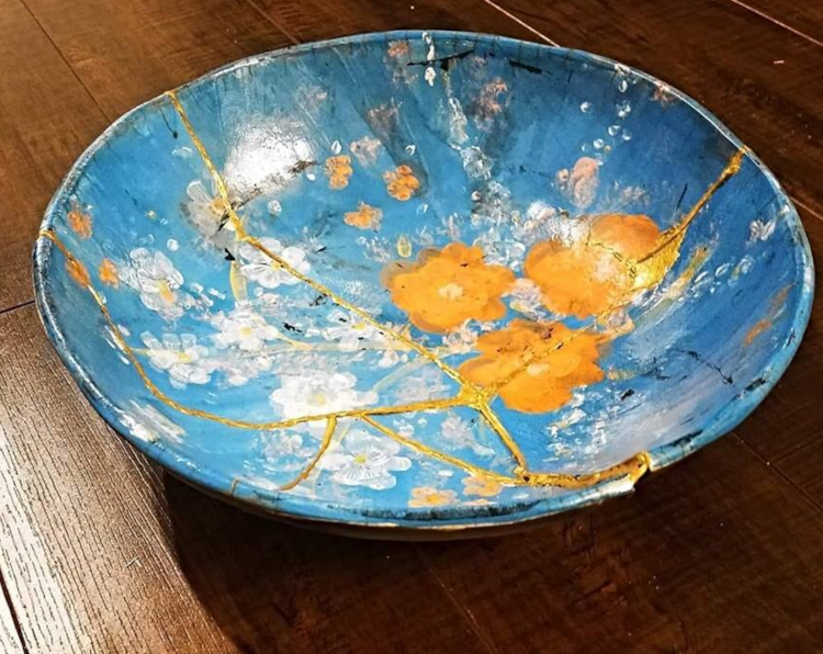 Photo von einer Keramikschüssel mit einer Blumendekoration in blau, weiß und orange. Die Schüssel war zwischenzeitlich zerbrochen und wurde mit Goldpulver wieder zusammengefügt. Für den Beitrag zum Tag der Fehler