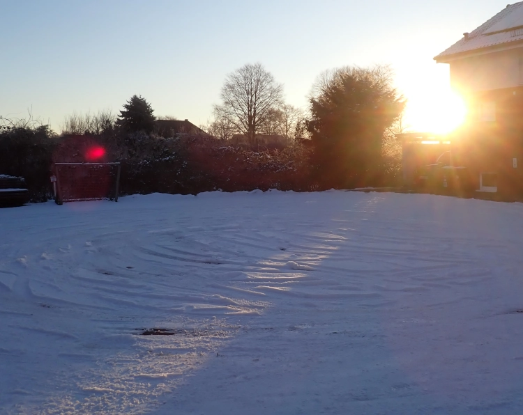Die Sonne geht über einem verschneiten Wendehammer auf.