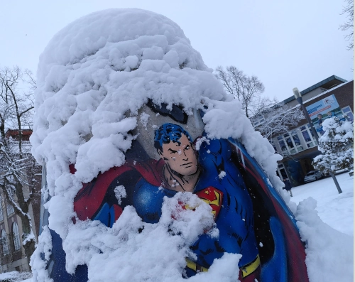 Ein glockenförmiger Poller aus Beton, darauf eine Zeichnung von Superman und Schneebelag