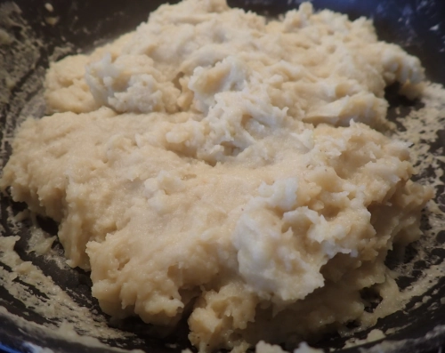 hellgelbes Linsen-Rührei in der Pfanne, die Masse ist insgesamt schon eingedickt, aber noch sehr feucht und weich, und sie klebt an der Pfanne