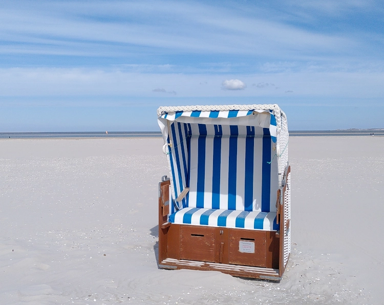 Ein blau-weiß gestreifter Strandkorb an einem Strand